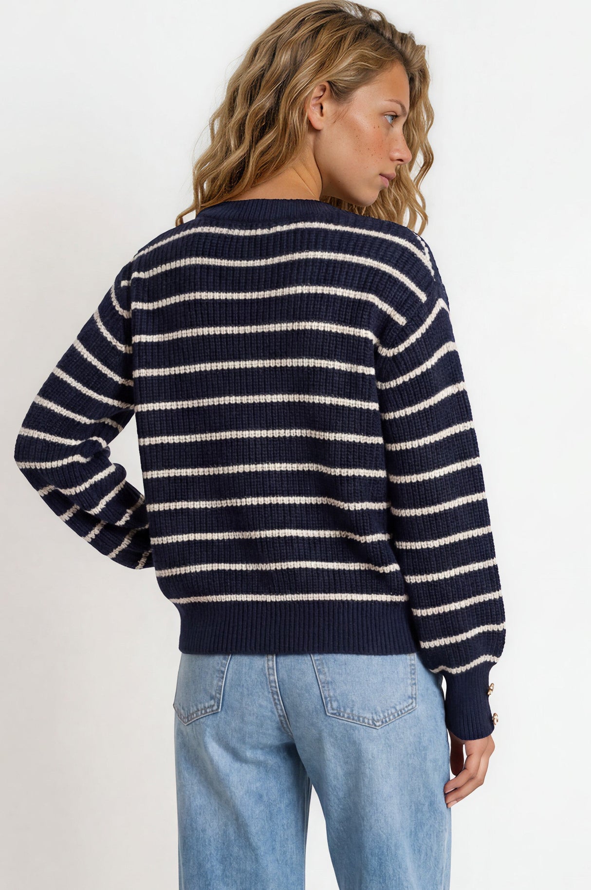 Person wearing a navy and white striped sweater and blue jeans on a white background