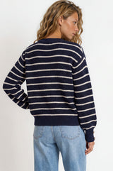 Person wearing a navy and white striped sweater and blue jeans on a white background