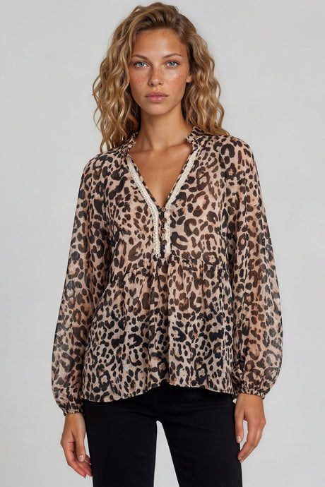 Woman wearing a leopard print blouse with lace trim on a plain background
