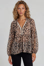 Woman wearing a leopard print blouse with lace trim on a plain background