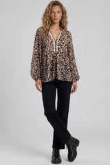Woman wearing a leopard print blouse with black pants and boots on a white background