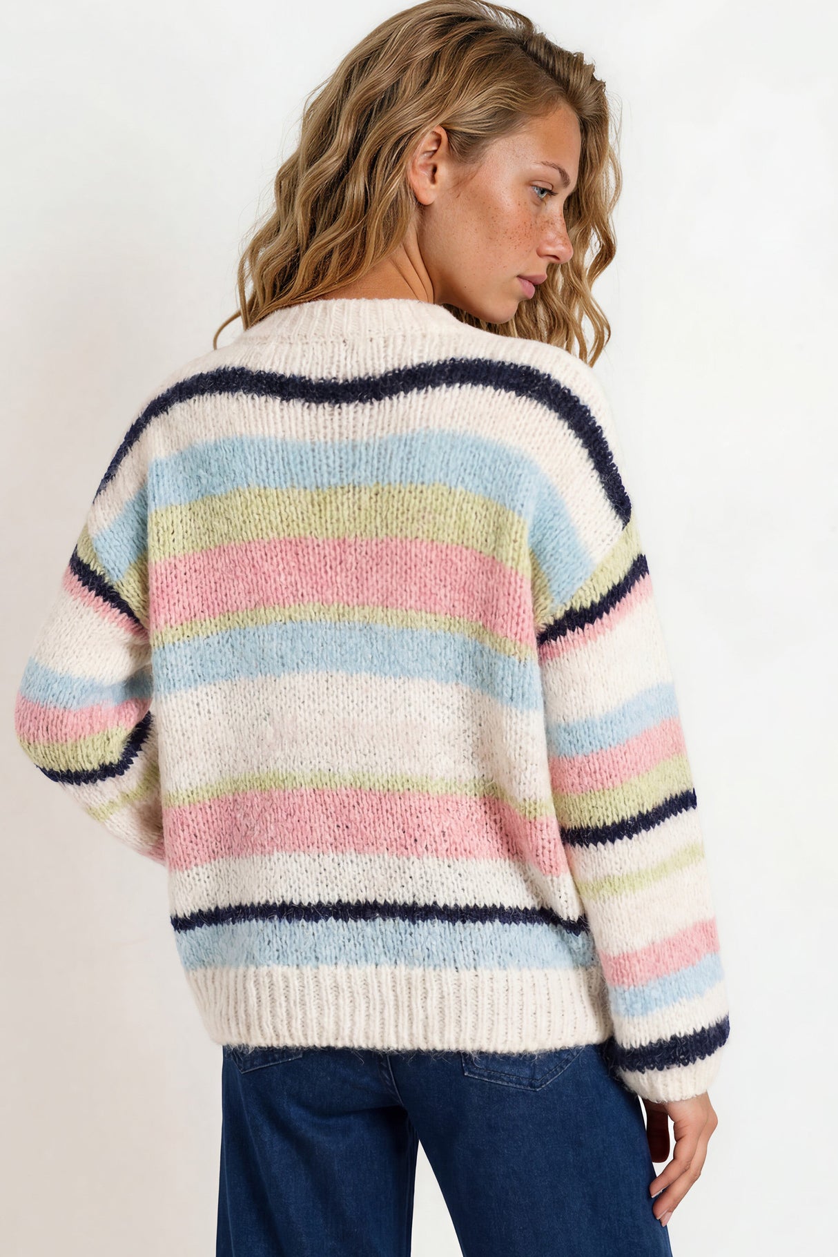 Woman wearing a colorful striped sweater against a white background