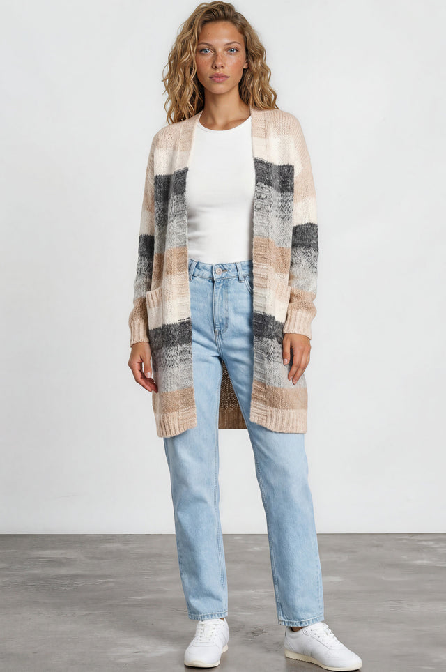 Woman wearing a plaid cardigan, white shirt, blue jeans, and white sneakers on a plain background
