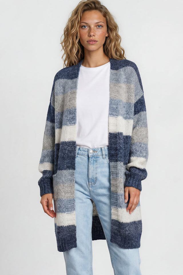 Woman wearing a long, plaid cardigan over a white shirt and light blue jeans on a plain background