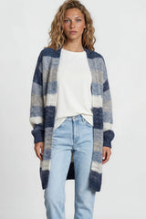 Woman wearing a plaid cardigan, white shirt, light blue jeans, and white sneakers on a plain background