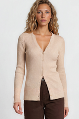 Woman wearing a beige cardigan and brown pants on a plain background