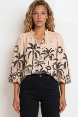Woman wearing a blouse with palm tree pattern against a plain background