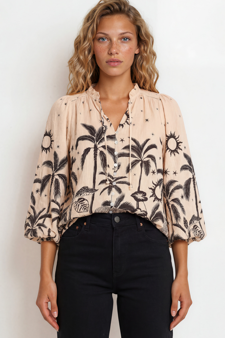 Woman wearing a blouse with palm tree pattern against a plain background