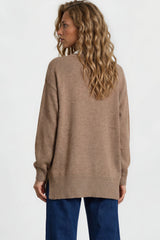 Woman wearing a beige sweater and blue pants on a white background