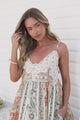 Video of a woman touching her hair in the Georgette Maxi Dress in Lyla Print, showing the white lace motif V-neck bodice, thin straps and floral stripe skirt against a white wall