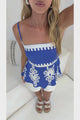 Video of a woman taking a mirror selfie in the Meg Cami in Maceo Print Blue, a navy spaghetti-strap peplum cami with white trim and white printed motifs, styled with white shorts and white sandals in a bright white room