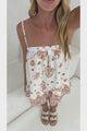 Video of a woman wearing the Clea Top in Andros Print, a white ruffle hem cami with a rust tiger and palm print, styled with white sandals