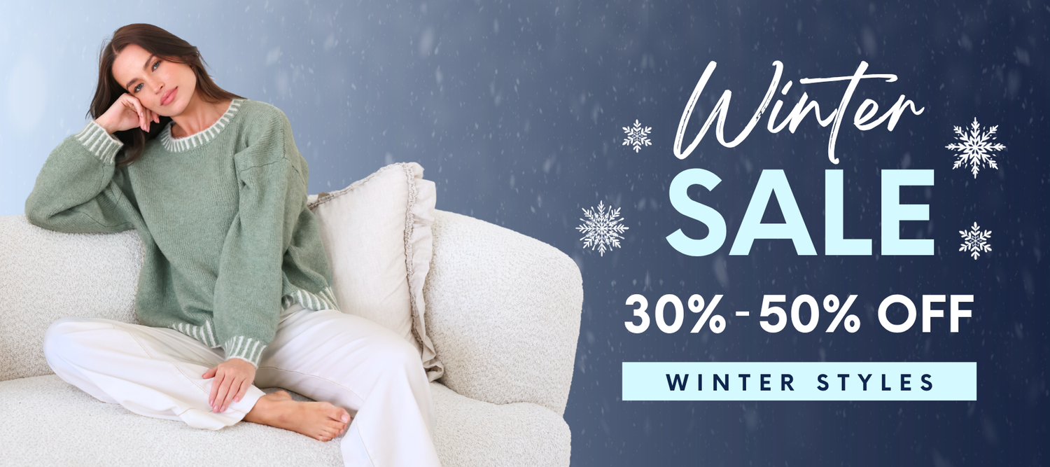A woman sits on a white sofa wearing a sage green knit sweater and white pants, with a dark blue winter-themed promotional banner on the right that reads 'Winter SALE 30%-50% OFF' and 'WINTER STYLES'.